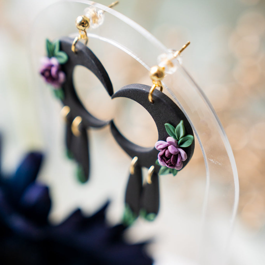 Black hoop earrings with floral accents on a blurred background